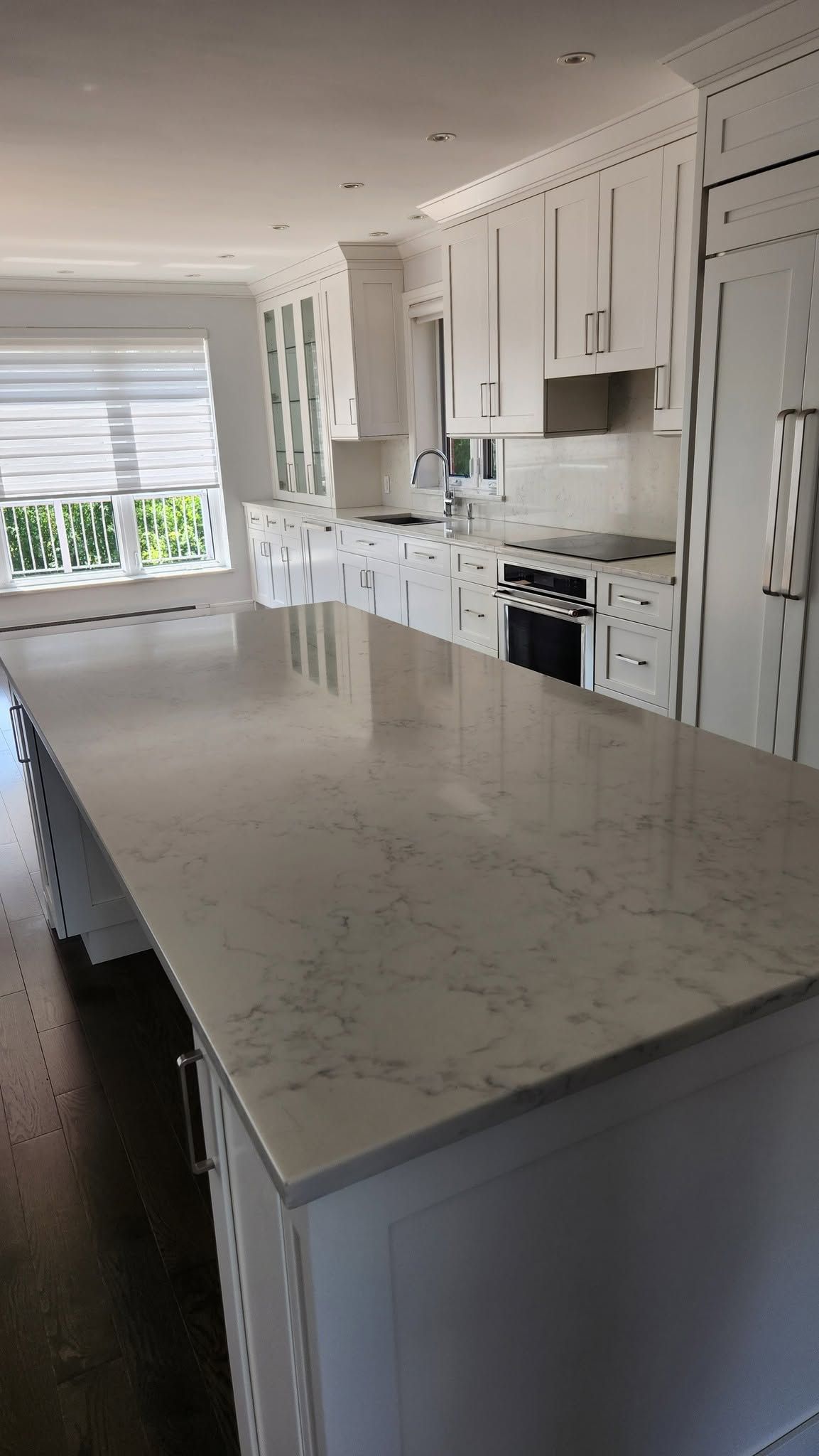 Cuisine résidentielle neuve, îlot de quartz dégagé et armoires blanches, livrée prête à occuper